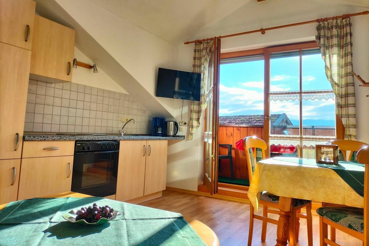 A kitchen with wooden cabinets, a built-in oven, and a window with curtains.