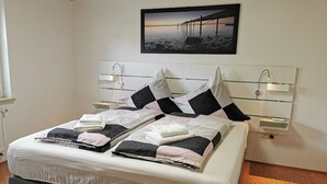 Una cama bien hecha con cabecera, dos mesitas de noche y un cuadro enmarcado sobre la cama.