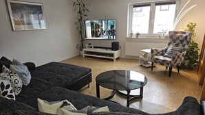 Una sala de estar con sofá, mesa de centro, televisor y una silla.