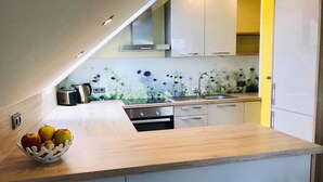 A modern kitchen with white cabinets, a wooden countertop, and a decorative backsplash. - Ferienwohnung Anna (Moosbach)