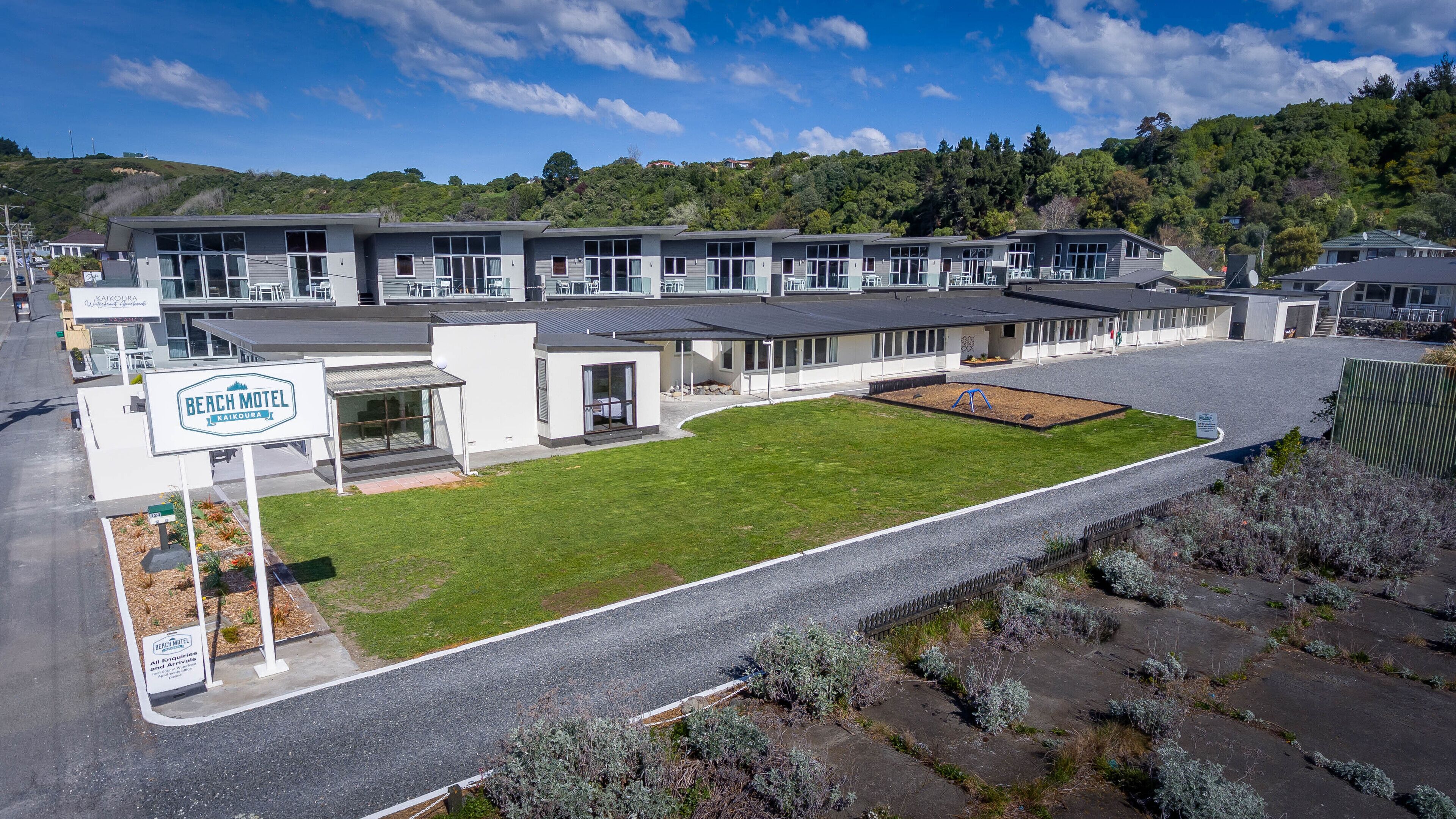 A modern motel with multiple units, a well-maintained lawn, and a parking area.