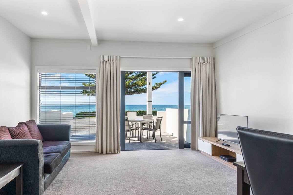 Une chambre d’hôtel moderne avec vue sur la mer, comprenant un canapé, un bureau et un coin repas.