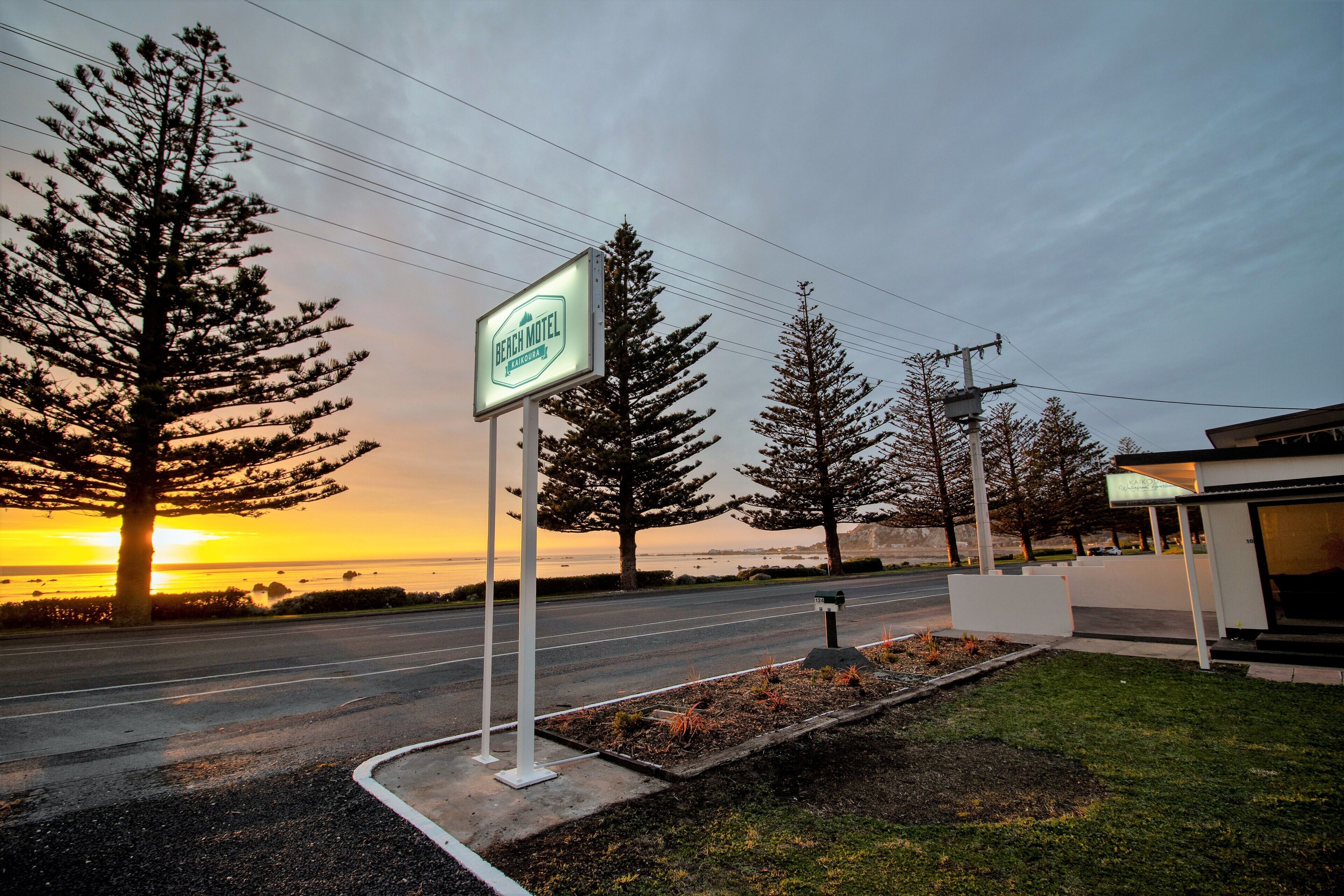 Schild eines Straßencafés, eine Straße und ein Sonnenuntergangsblick auf das Meer.