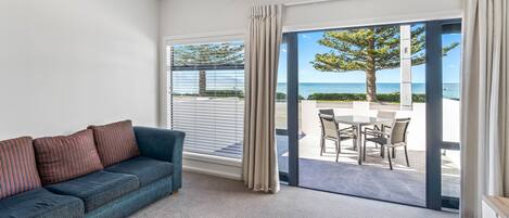 A living room with a sofa and a view of the sea through large glass doors.