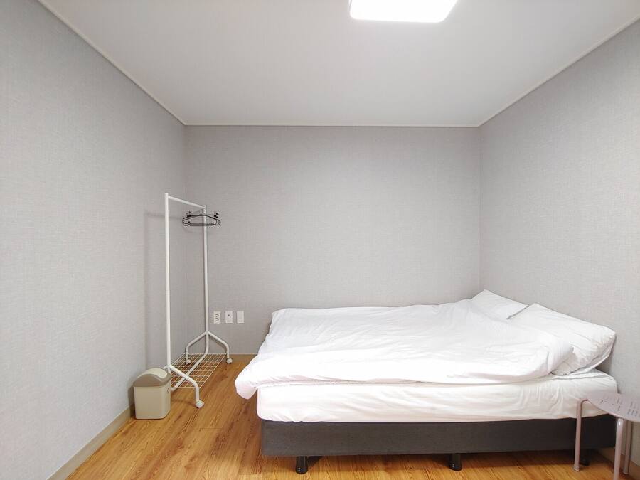 A small, neatly arranged bedroom with a single bed, a bedside table, and a wall-mounted radiator.