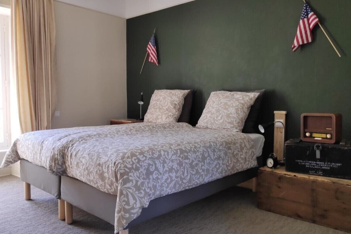 Een slaapkamer met een bed, twee nachtkastjes, een Amerikaanse vlag, een klok en een radio.