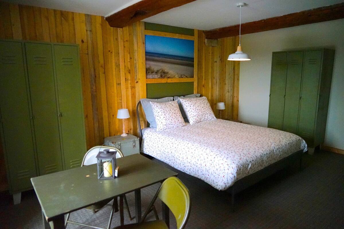 Een kamer met een bed, een tafel, een stoel en groene kasten.