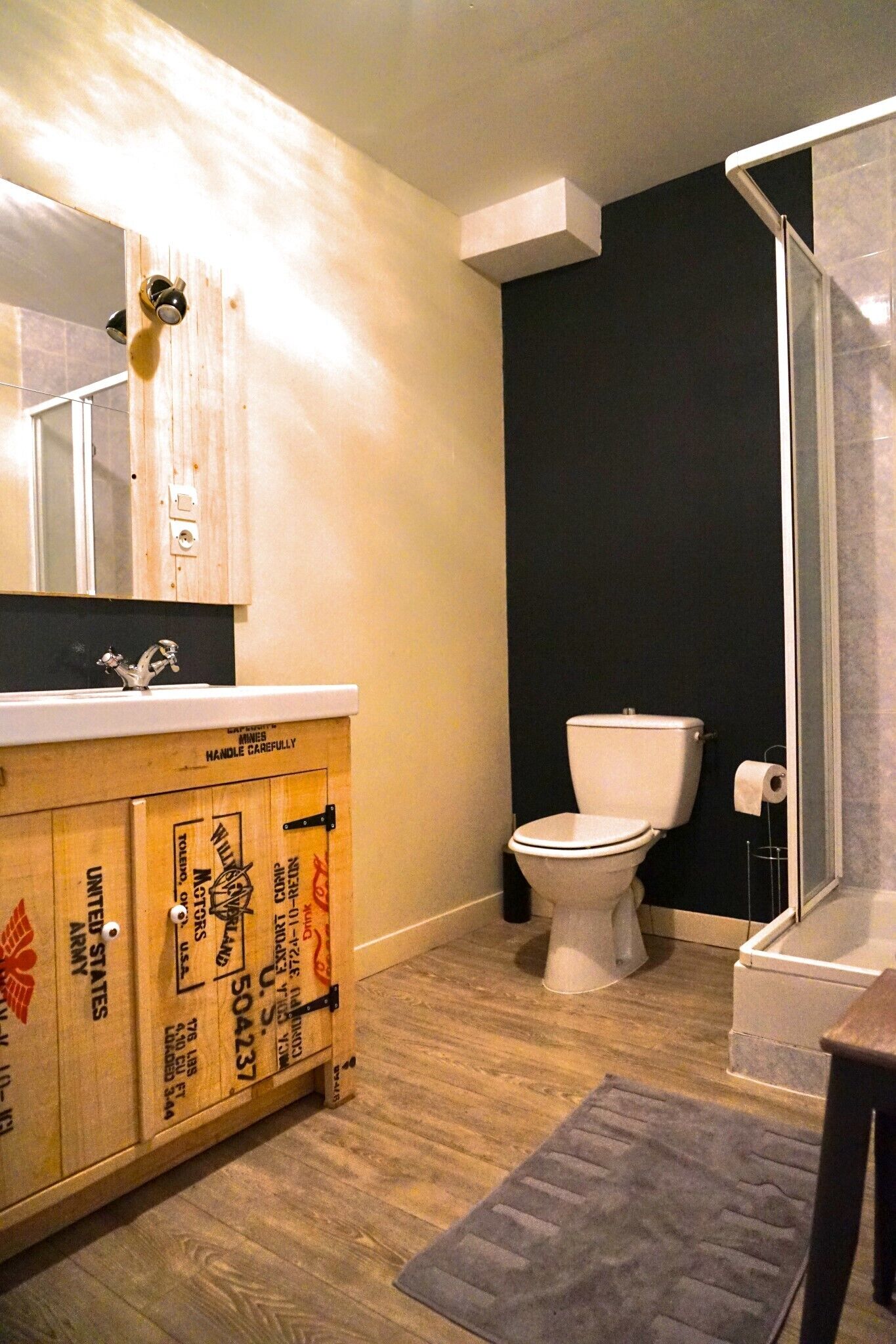 Un baño con tocador de madera, inodoro y zona de ducha.