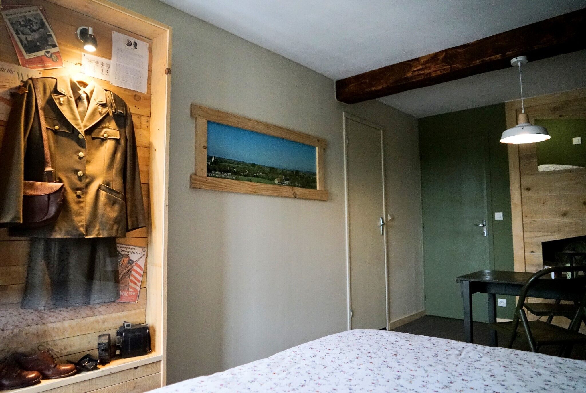 A room with a bed, a wooden cabinet with shoes, a framed picture, and a desk with a chair.