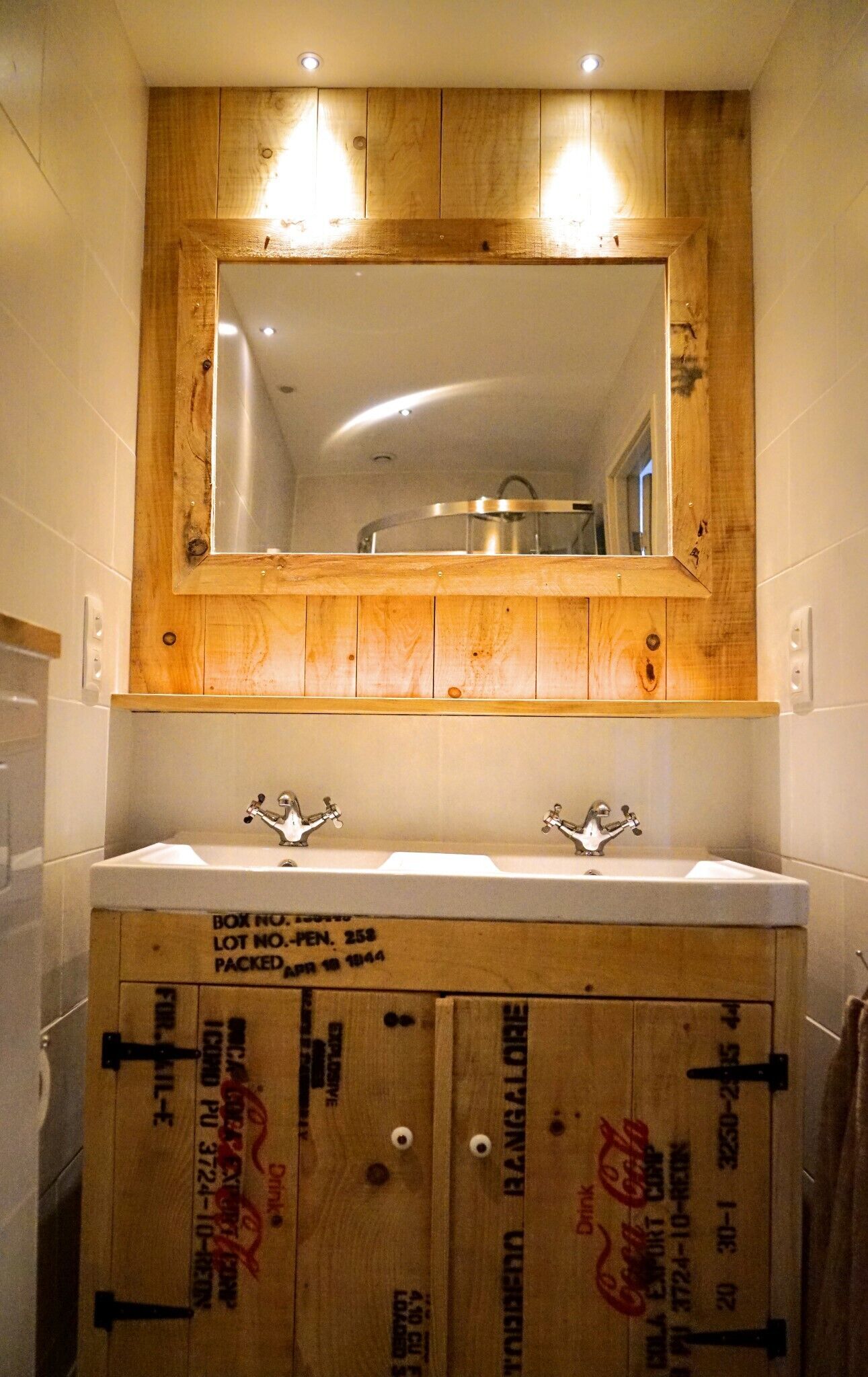 A bathroom with a wooden vanity, two sinks, and a mirror above.