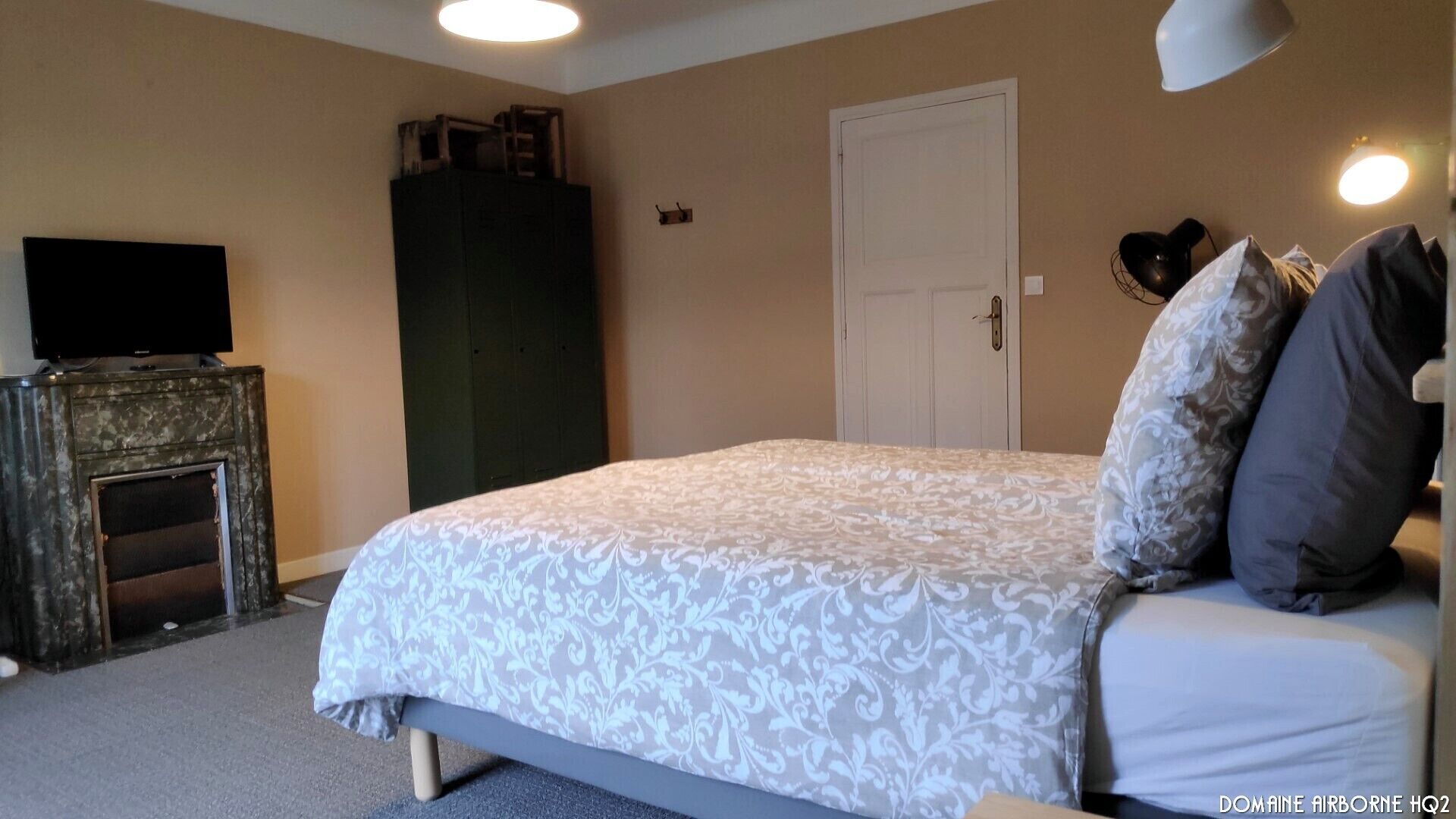 Une chambre à coucher avec un lit, un téléviseur posé sur un meuble, une armoire et une porte.