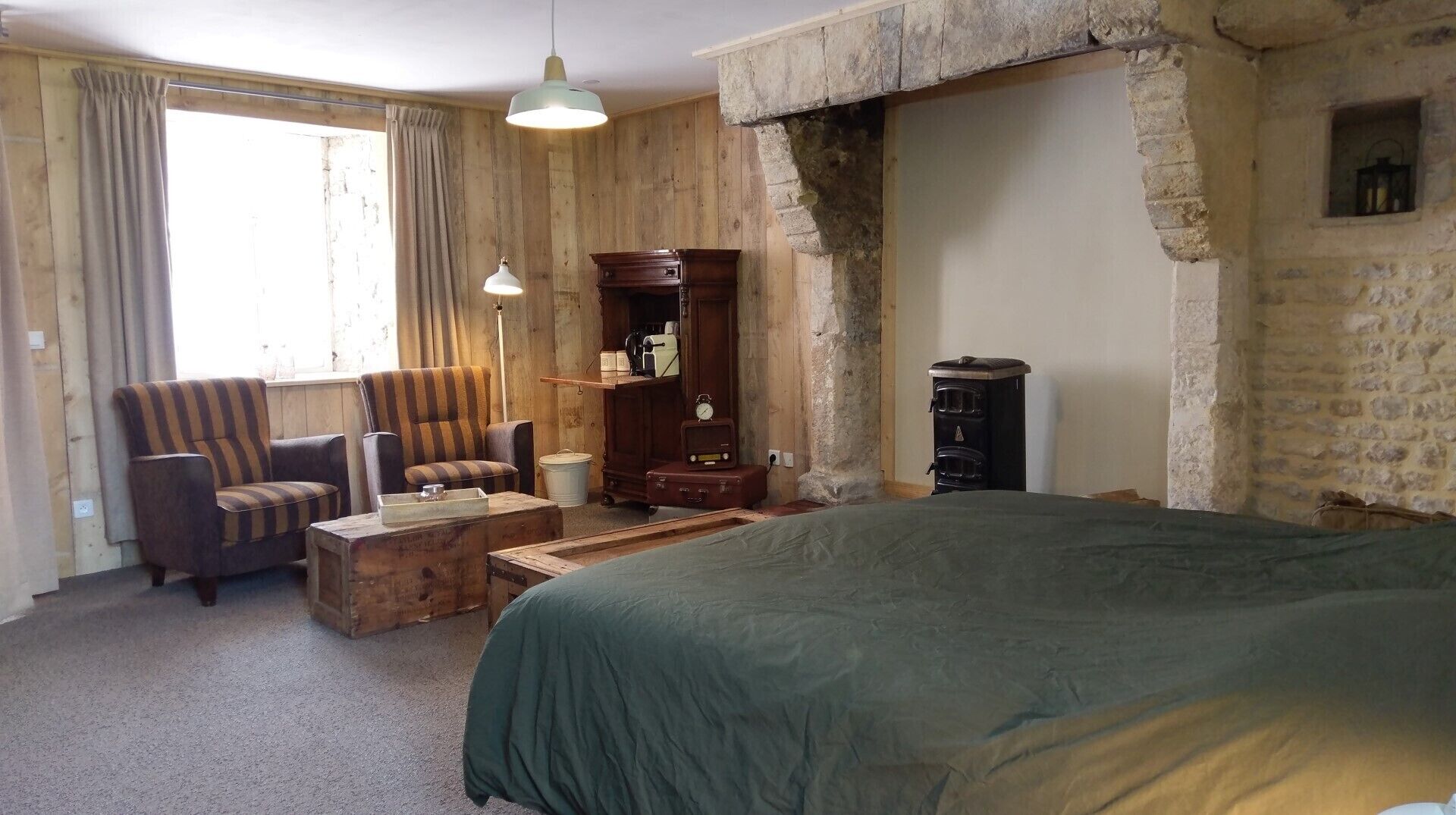 A cozy hotel room with a large bed, a wooden dresser, a chair, and a small table.