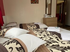 A hotel room with two beds, a wooden dresser, a mirror, and a red curtain.