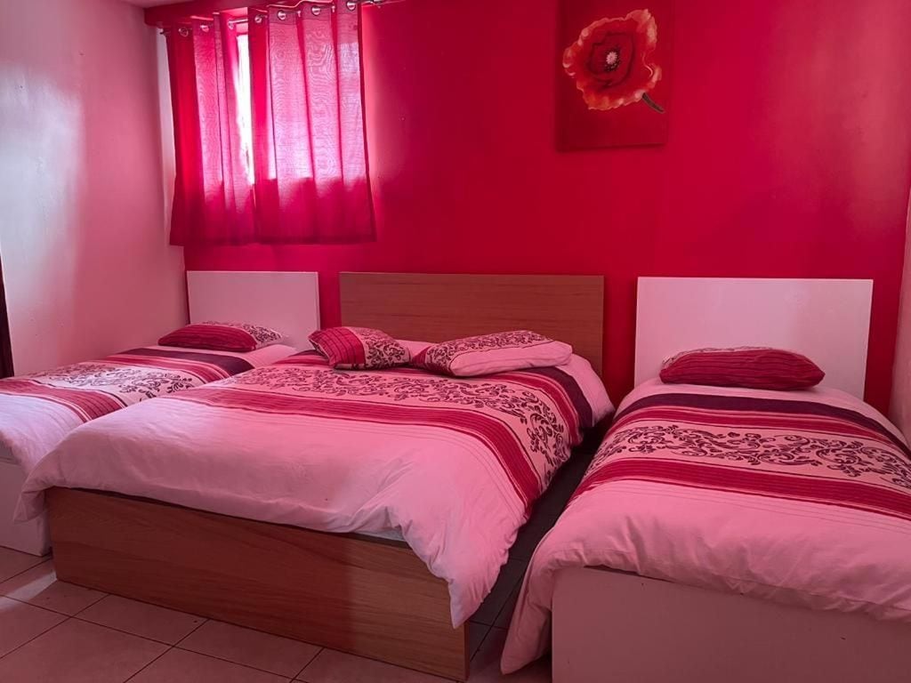 A room with two beds, each with a wooden headboard and pink bedding.