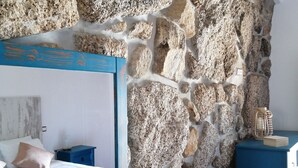 Ein Schlafzimmer mit Etagenbett, Steinwand, Nachttisch und Kommode.