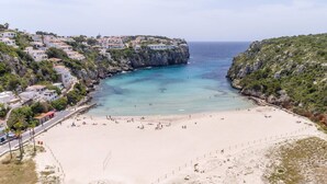 A coastal town with a sandy beach, clear turquoise waters, and buildings on a hillside. - VILLA AMALIA Family chalet. Private Pool, Free AC / Wi-fi (Cala en Porter)