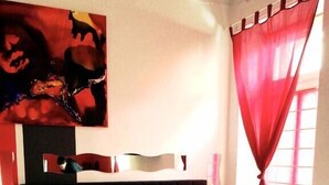 Ein Hotelzimmer mit zwei Betten, einem großen Gemälde an der Wand und roten Vorhängen.
