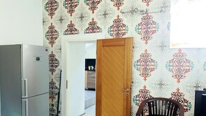 Eine kleine Küche mit Kühlschrank, einer Holztür und einem Esstisch mit Stühlen.