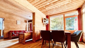 Een houten interieur met een bank, stoelen, een tafel en een televisie.