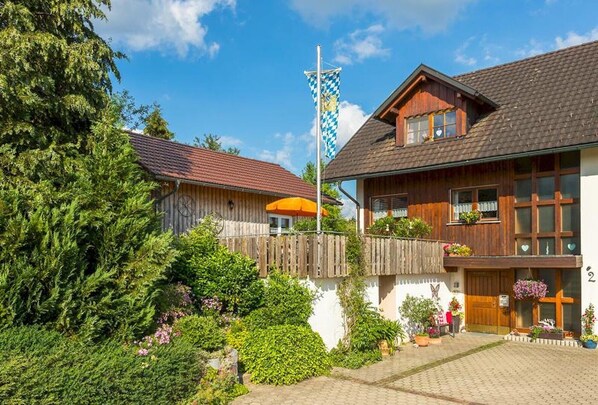 A traditional wooden house with a checkered flag, a wooden fence, and a well-maintained garden.