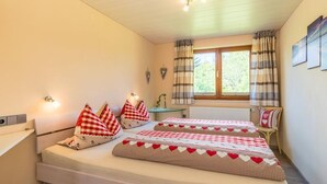 Una habitación con dos camas, una ventana con cortinas, una mesa y luces en la pared.