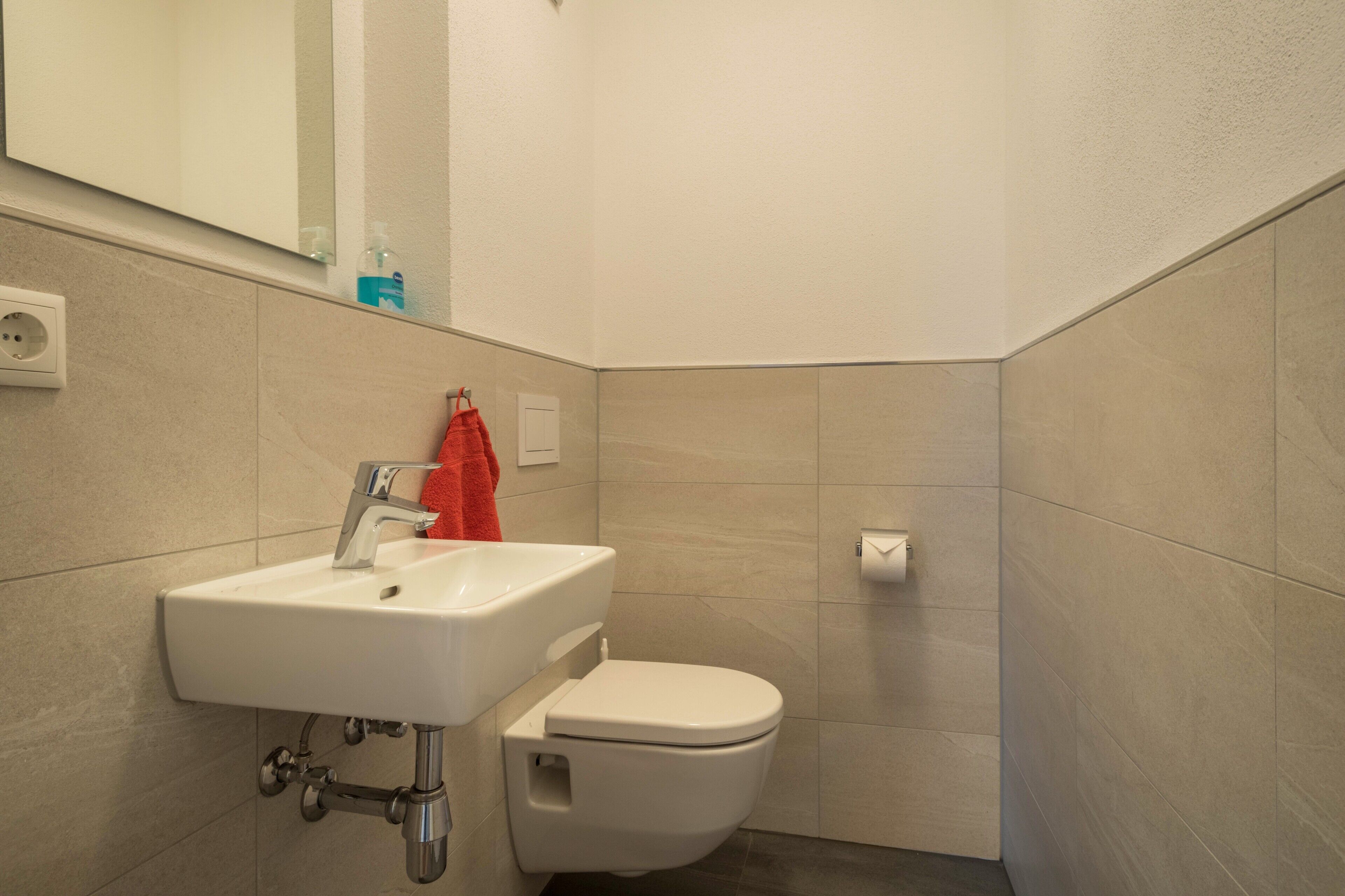 A bathroom with a white sink, a toilet, and a mirror.