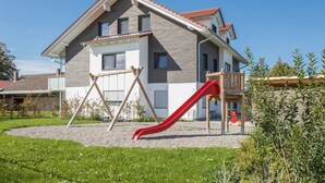 A modern two-story house with a red slide in the yard.