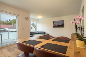 Un comedor con una mesa de madera, manteles individuales negros y sillas marrones.
