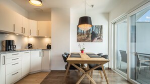 Una cocina moderna con armarios blancos, una mesa de comedor de madera y un amplio ventanal.