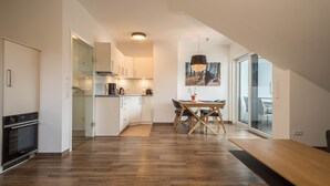 Una cocina moderna con zona de comedor, suelo de madera y un amplio ventanal.