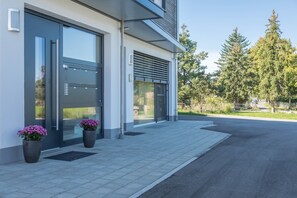 A modern building with large glass doors, potted plants, and a paved walkway.