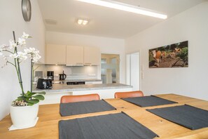 Una cocina moderna con comedor, un reloj en la pared y un cuadro con vacas.