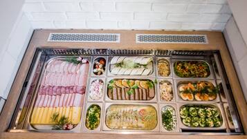Een buffet met diverse soorten eten, waaronder vleeswaren, kazen en salades.