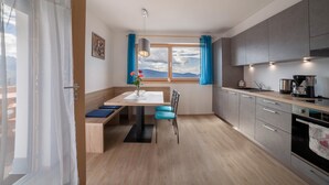 A modern kitchen with a dining area, a large window with a view, and a built-in oven.