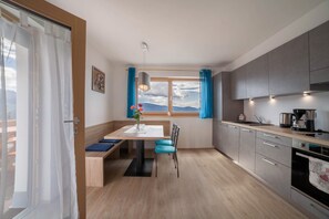 A modern kitchen with a dining area, a large window with a view, and a built-in oven.