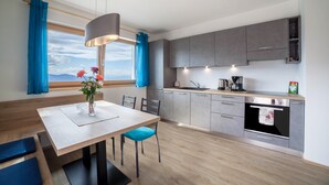 A modern kitchen with a dining area, large windows, and a view of the mountains.