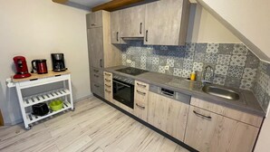 Uma cozinha compacta com armários de madeira, forno embutido, lava-louças e painel de azulejos.