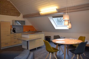 A modern kitchen with a skylight, a dining area with chairs, and a sofa.