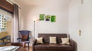 En stue med en brun sofa, et spisebord, en stol og tre billeder hængt på væggen.