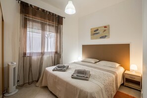 A bedroom with a bed, a bedside lamp, a heater, and a window with curtains. - "Beach Residence 01" with Terrace, Barbecue, Wi-Fi & Cable TV; Parking Available (Armação de Pera)