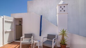 A small outdoor seating area with two chairs and a table, a potted plant, and a white wall with a window. - "Beach Residence 21" with Balcony, Barbecue, Wi-Fi & Cable TV; Parking Available (Armação de Pera)