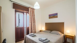 A bedroom with a bed, bedside lamps, a door, and a painting on the wall. - "Beach Residence 21" with Balcony, Barbecue, Wi-Fi & Cable TV; Parking Available (Armação de Pera)
