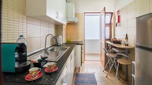 A compact kitchen with a coffee maker, sink, and a dining area with chairs. - "Beach Residence 21" with Balcony, Barbecue, Wi-Fi & Cable TV; Parking Available (Armação de Pera)