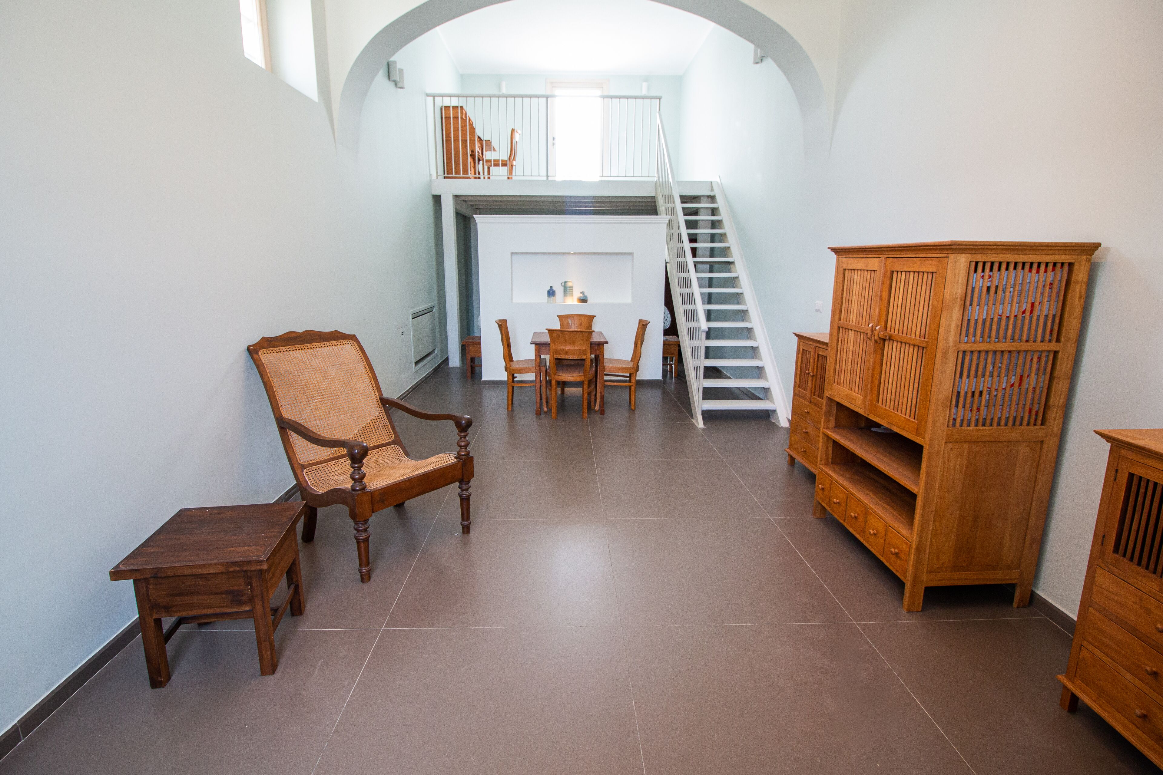 Um quarto amplo com uma mesa de jantar, cadeiras, um armário de madeira e uma escada que leva a um andar superior.