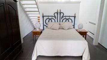 Un dormitorio con una cama grande, un armario de madera oscura, una escalera y dos mesitas de noche con lámparas.