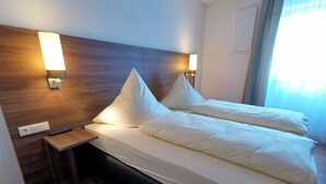 A hotel room with a wooden headboard, two bedside tables, a bed with white linens, and wall-mounted lamps. - Whg.5 Ferienwohnung Landglück (Bechhofen)