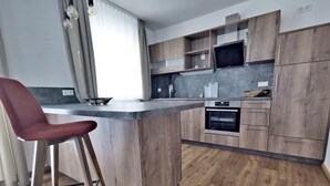 A modern kitchen with wooden cabinets, a central island, and a bar stool. - Whg.5 Ferienwohnung Landglück (Bechhofen)