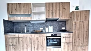 Eine moderne Küche mit Holzschränken, einem Einbauofen und einer grauen Arbeitsplatte.