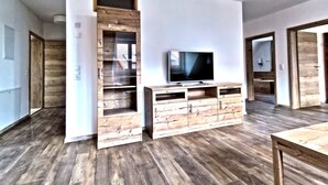 Ein modernes Wohnzimmer mit einem Holzboden, einer TV-Konsole, Einbauschränken und einem Flachbildfernseher.