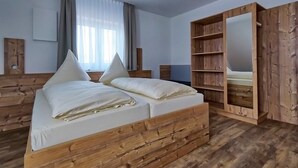 Ein Schlafzimmer mit einem hölzernen Bett, einem großen Spiegel und einem Kleiderschrank mit vielen Regalen.